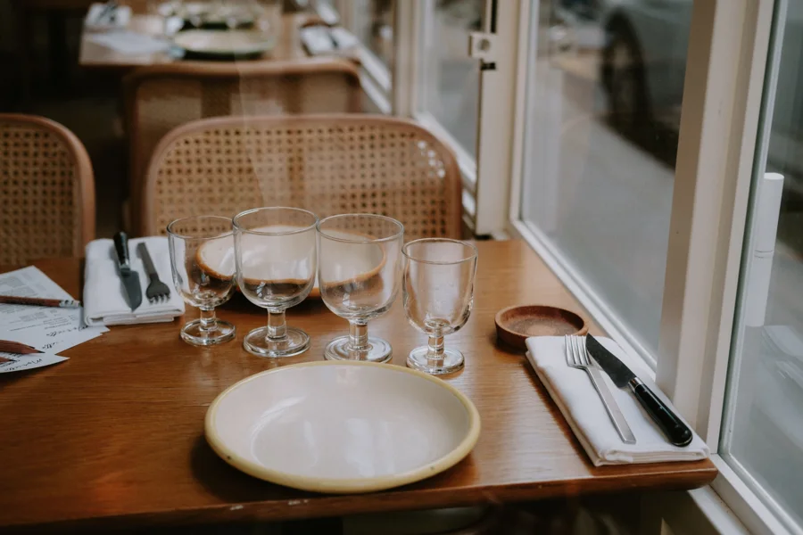 Table dressée près de la vitrine d'un bistrot, verres et assiettes en attente du service