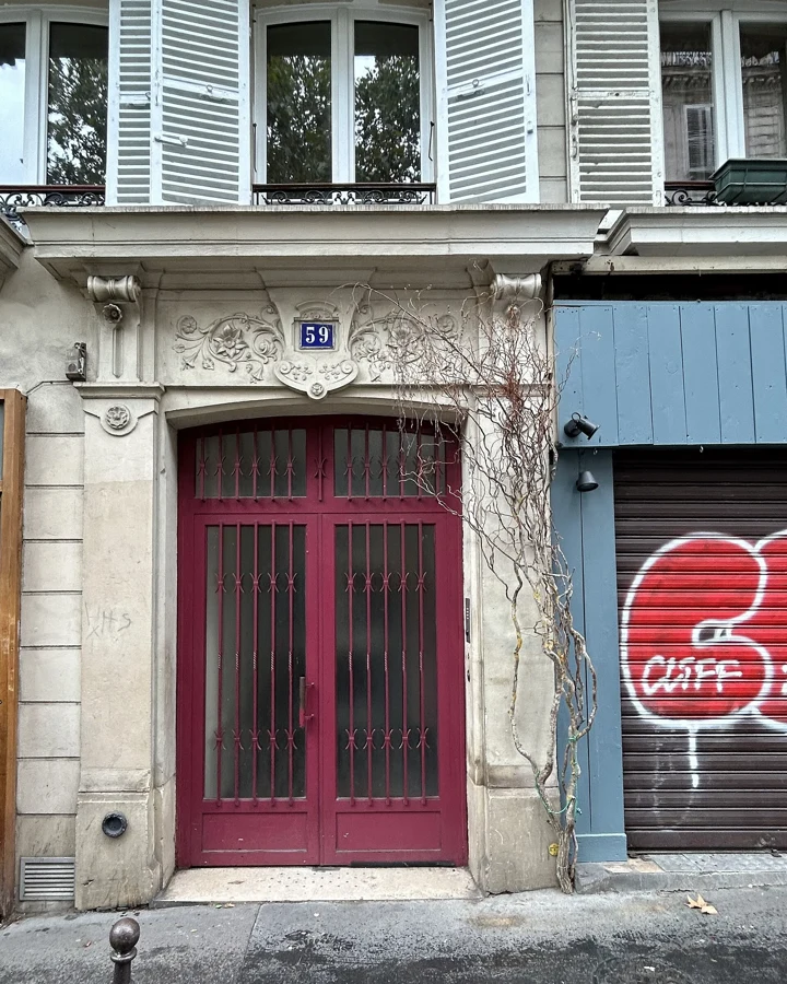 Entrée d'immeuble haussmannien au 59 rue des Martyrs, porte bordeaux et façade en pierre